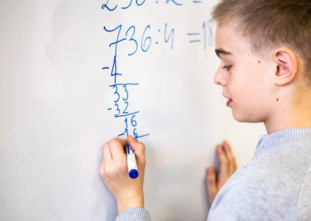 istock Close up schoolboy writing numbers on white board 1142029324