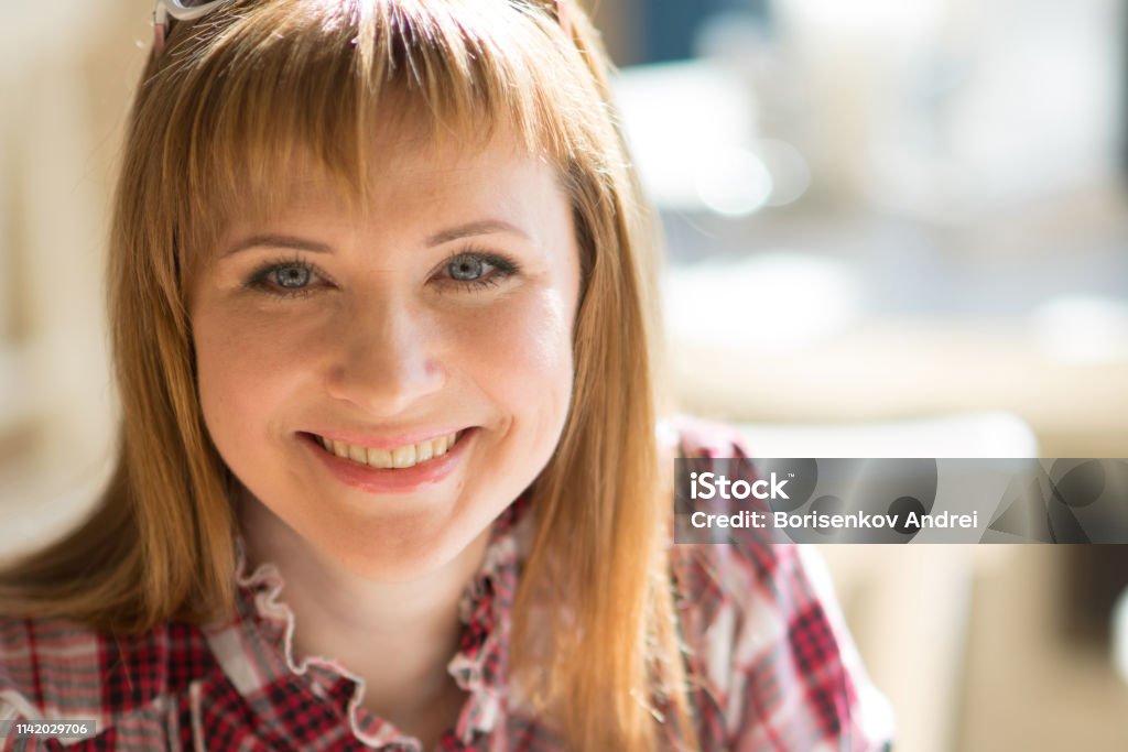 Uma menina em um café do verão, sentando-se em uma grande janela. A menina sorri. Close-up - Foto de stock de Adolescente royalty-free