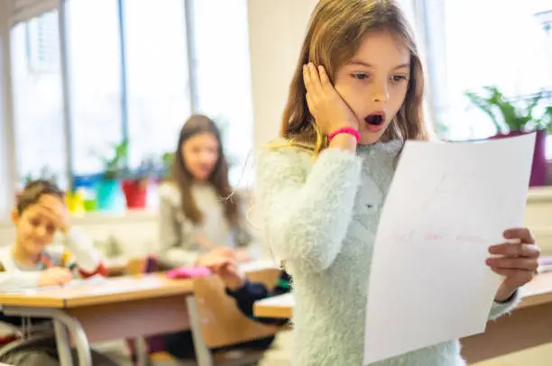 Cute small girl is unhappy because bad grade on the test