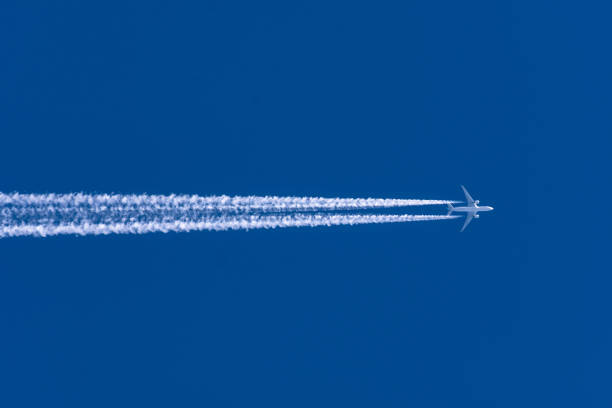 Airplanes leaving contrail trace from left to right on a clear blue sky.