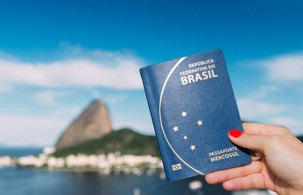 Hand holding Brazilian passport with SugarLoaf Mountain in Rio de Janeiro, Brazil in background stock photo