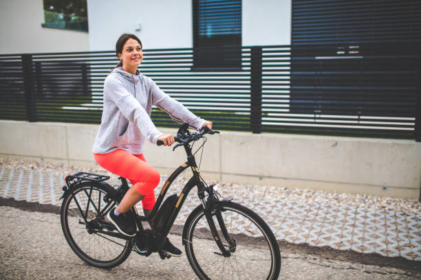 그녀의 전기 자전거를 타고 여자 - healthy lifestyle exercise equipment exercising exploration 뉴스 사진 이미지