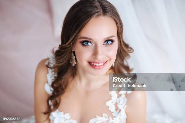 Beautiful Bride With Long Curly Hair In Elegant Wedding Dress And Diadem Smiling In Room In The Wedding Morning Stock Photo - Download Image Now