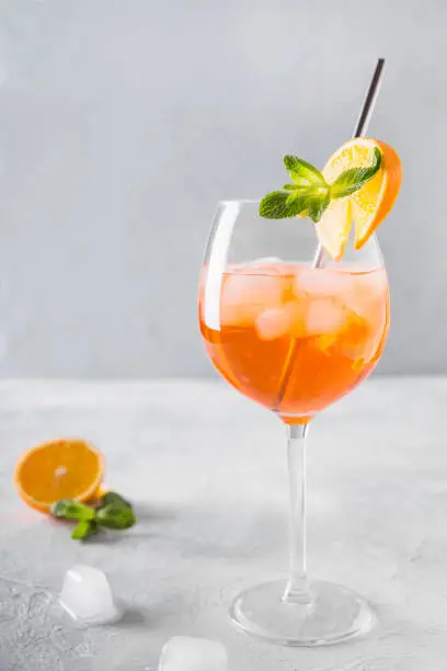 Classic Italian Spritz cocktail in wine glass with metal straw on light. Close up.