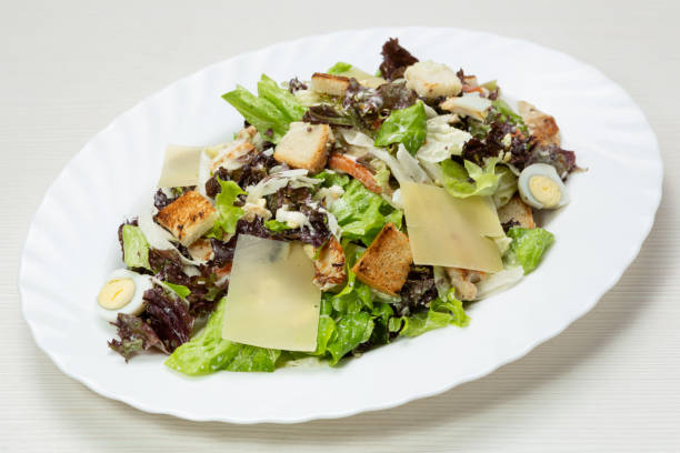istock Caesar salad, with quail eggs, on a white oval plate 1142037235