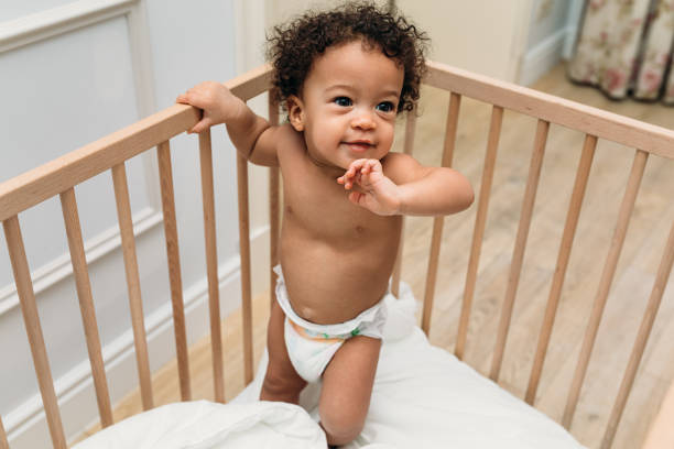 istock Curly haired toddler wearing a diaper in a crib 1142040333