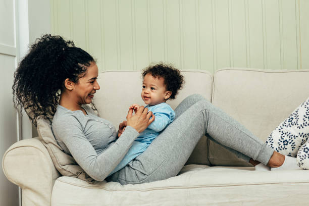 istock Side view of mother lying on couch and playing with her son 1142040416