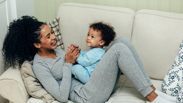 istock Mother playing with baby boy lying on sofa 1142040464