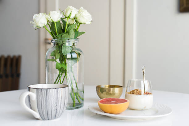 istock Healthy breakfast. Ingredients: grapefruit, granola, tea, lychee. Vase of roses. Side view, white background 1142044117