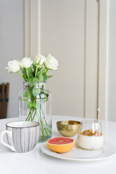 istock Healthy breakfast. Ingredients: grapefruit, granola, tea, lychee. Vase of roses. Side view, white background 1142045052