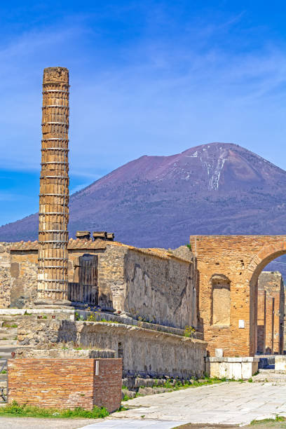Temple column (Temple of Giove), street and buildings at the ancient Roman city of Pompeii, Italy. which was destroyed by mount Vesuvius (seen in background) volcanic eruption in AD 79