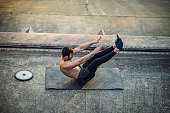 Young Shirtless Muscular Man Training with Weights Outdoors at the Sunset