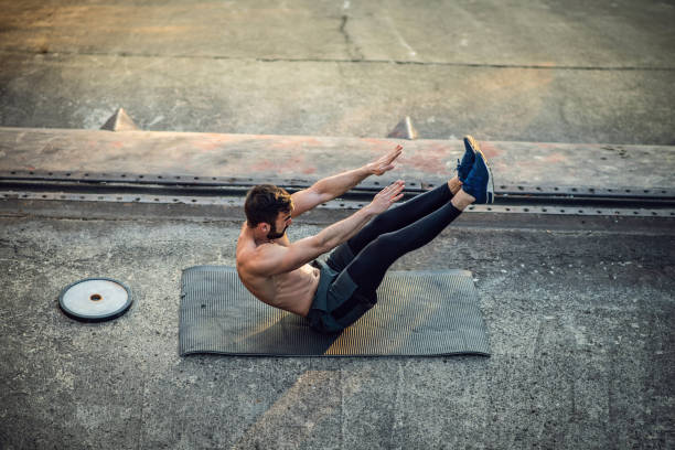 młody shirtless muscular man szkolenia z ciężarami na zewnątrz o zachodzie słońca - sit ups zdjęcia i obrazy z banku zdjęć