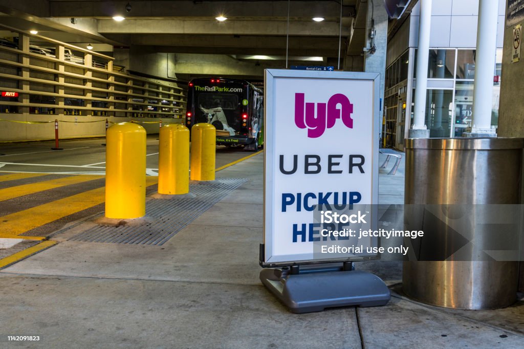 Ride sharing companies Lyft and Uber pickup spot at the airport. Lyft and Uber have replaced many Taxi cabs for transportation I Indianapolis - Circa July 2017: Ride sharing companies Lyft and Uber pickup spot at the airport. Lyft and Uber have replaced many Taxi cabs for transportation I Uber - Brand-Name Stock Photo