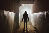 Creepy silhouette with knife  in the dark abandoned building. Horror about maniac concept