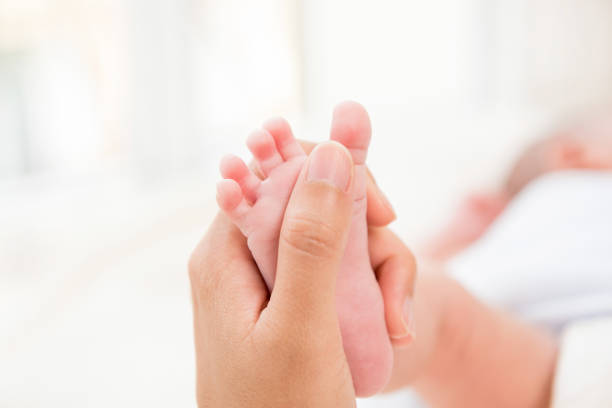 istock Mother hand gently touch small baby foot 1142099839