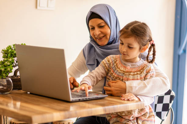 istock Muslim mother playing with her daughter, sitting on the Internet 1142101103