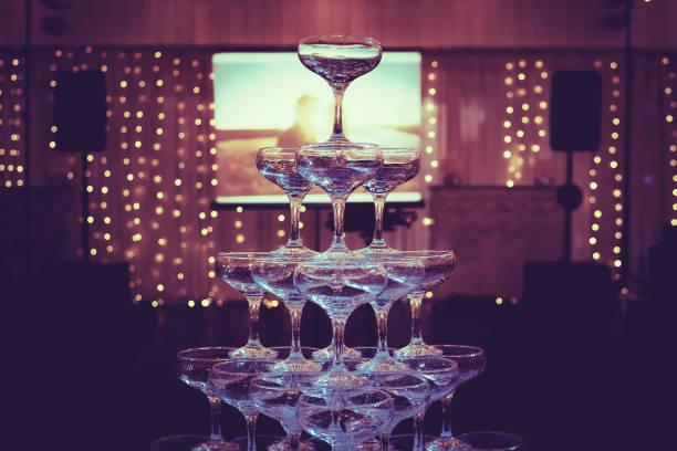 built champagne tower in the background of a loving couple projected photo. glasses tower in the dark illuminated banquet hall. champagne wedding tower in the centre of fabulous wedding room - banquet table set restaurant imagens e fotografias de stock