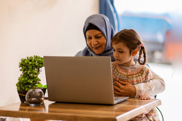istock Muslim mother is teaching her daughter how to use computer sitting on her lap 1142101505
