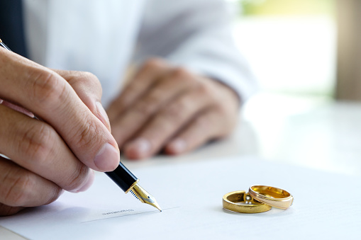 Hand man woman on paper with marry ring on paper to sign marriage or divorce
