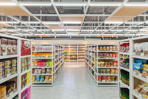 Abstract blurred supermarket aisle with colorful shelves and recognizable customers as background