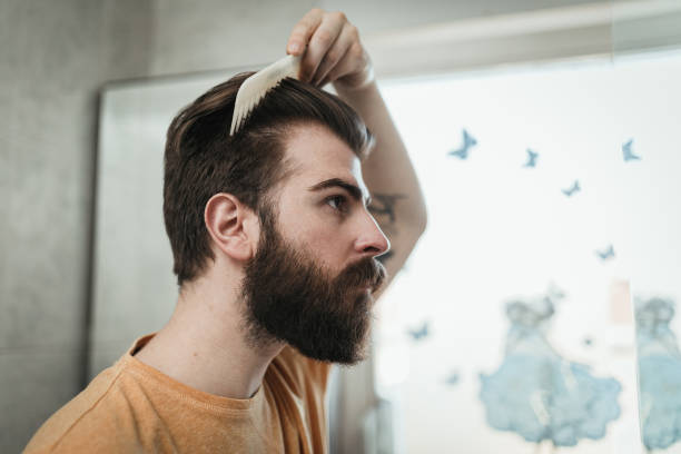 istock Young handsome man combing hair in the bathroom 1142105284
