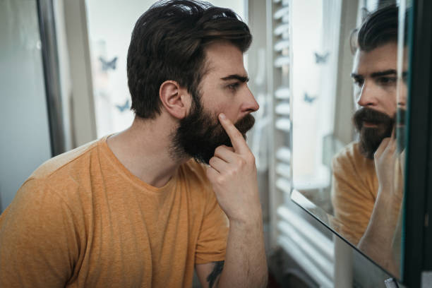 istock Young man looking into mirror and covering eye bags 1142105356