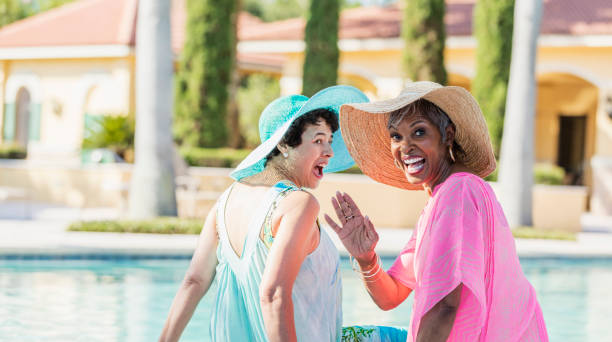 istock Two senior women sitting on pool deck, feet in water 1142107650