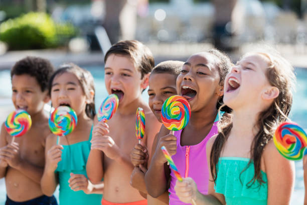 istock Multi-ethnic children licking lollipops by swimming pool 1142109261