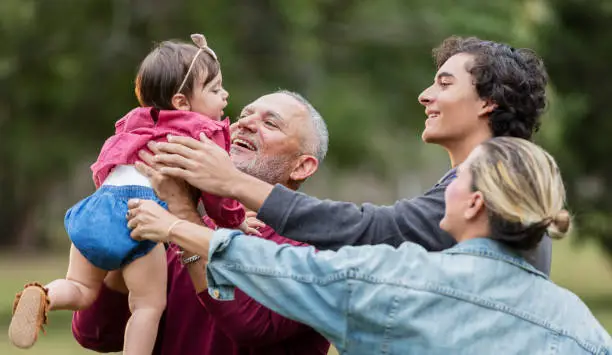 Photo of Multi-generation Hispanic family, grandfather holds baby