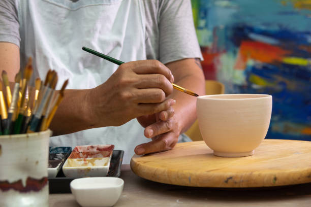 istock Hand on  working In his pottery studio. Ceramic workshop. Paint on clay cup in the pottery. 1142117686