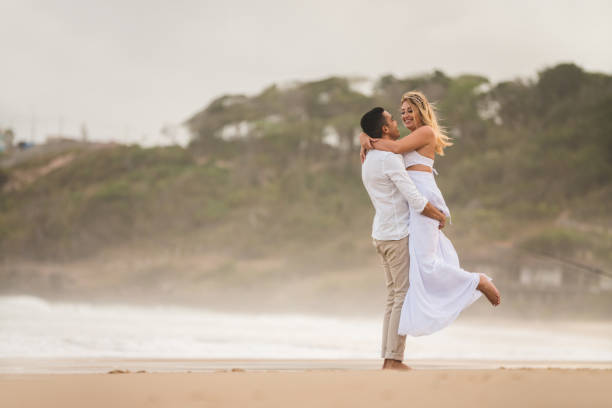 matrimonio in fuga, sposo abbraccia e solleva sposa - wedding beach bride groom foto e immagini stock