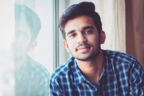 University Student, Portrait, Positivity, Aspirations - Young Man Seated Near a Window and Looking at the Camera for a Portrait