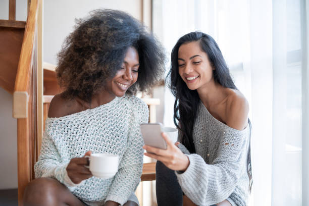 istock Girlfriends drinking coffee and using smart phone, in hotel room. 1142137567