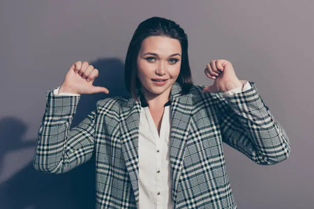 Closeup photo portrait of cunning attractive looking at camera pointing at herself smiling she her lady wearing stylish plaid checkered blazer isolated grey background.