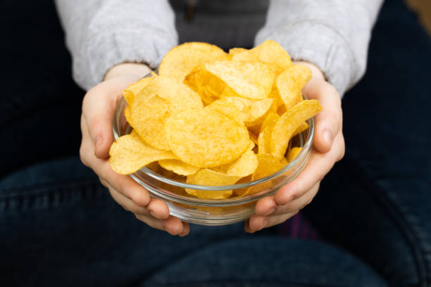 istock Female hand giving crispy potato chips bowl 1142140337