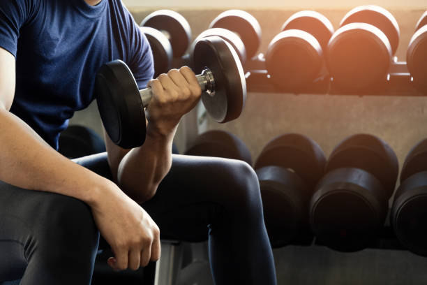 istock Handsome man playing biceps with dumbbell exercise to strong arm and body sit on black bench at gym fitness background. 1142141814