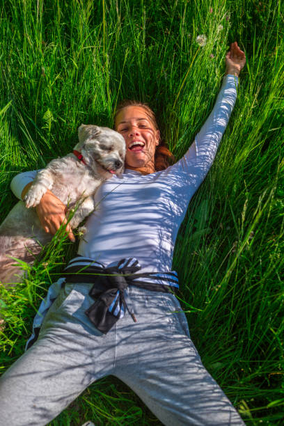 istock Smiling Young Woman Lying in Grass With Her Dog 1142147856