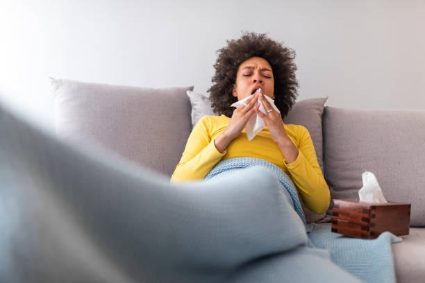 istock Young woman with cold blowing her runny nose. 1142148758