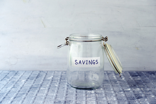 Empty glass money jar with savings label, financial concept.
