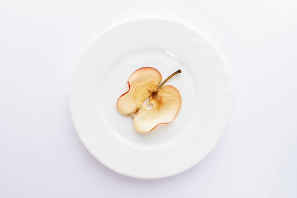 istock One thin slice of dried apple on round white plate on white background. 1142154025