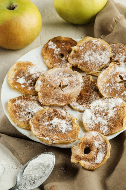 istock Apple chips with powdered sugar and cinnamon on beige fabric on background whole apples. 1142154044