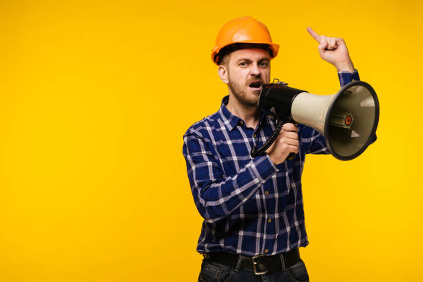 istock Angry worker man with a megaphone on yellow background 1142156522