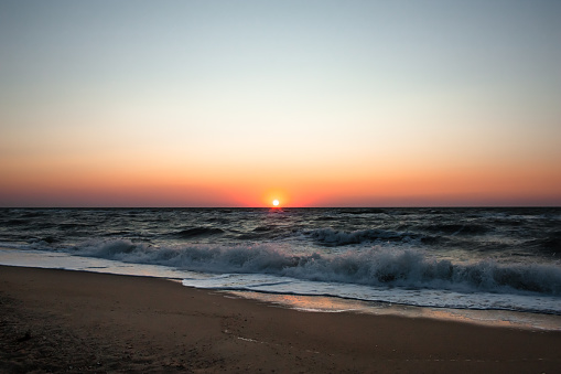 Sea ​​beach at sunrise. Sea ​​waves on a sandy beach. Tropical vacation background. Natural landscape. Sunset ocean horizon sky landscape. Blue ocean waves. Colorful ocean beach sunrise