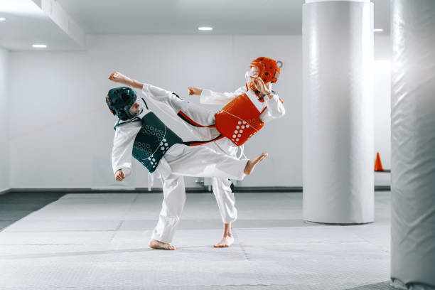 ragazzi sportivi caucasici che si allenano taekwondo in palestra bianca e si prendono a calci l'un l'altro. - tae kwon do foto e immagini stock