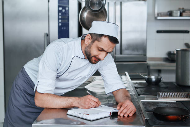 istock Focus on food safety. Happy chef cook standing in commerical kitchen 1142169917
