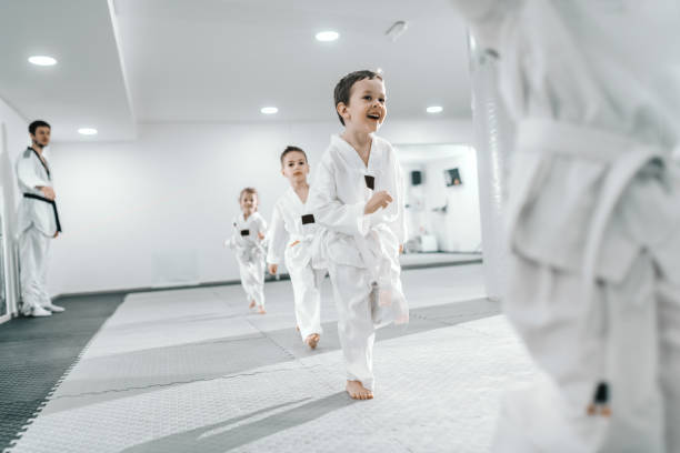 Small group of children having training at taekwondo class. All dressed in doboks. White background. Small group of children having training at taekwondo class. All dressed in doboks. White background. martial arts stock pictures, royalty-free photos & images
