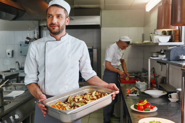 The New Tradition is Good Nutrition. Chef cooking tasty dish in commercial kitchen stock photo