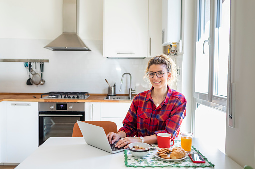 young woman using laptop at kitchen