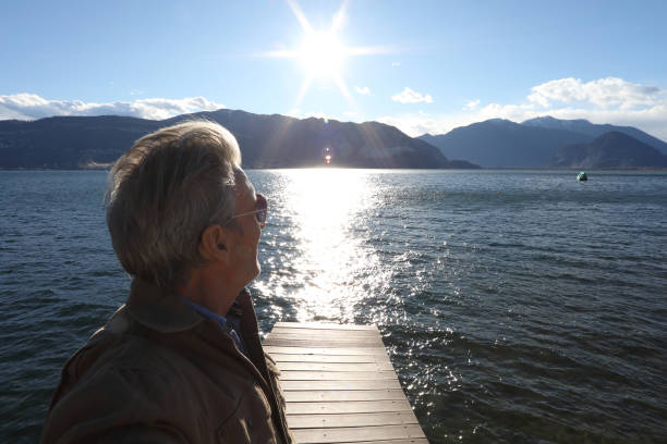istock View past man on dock to lake, sun and mountains 1142179367
